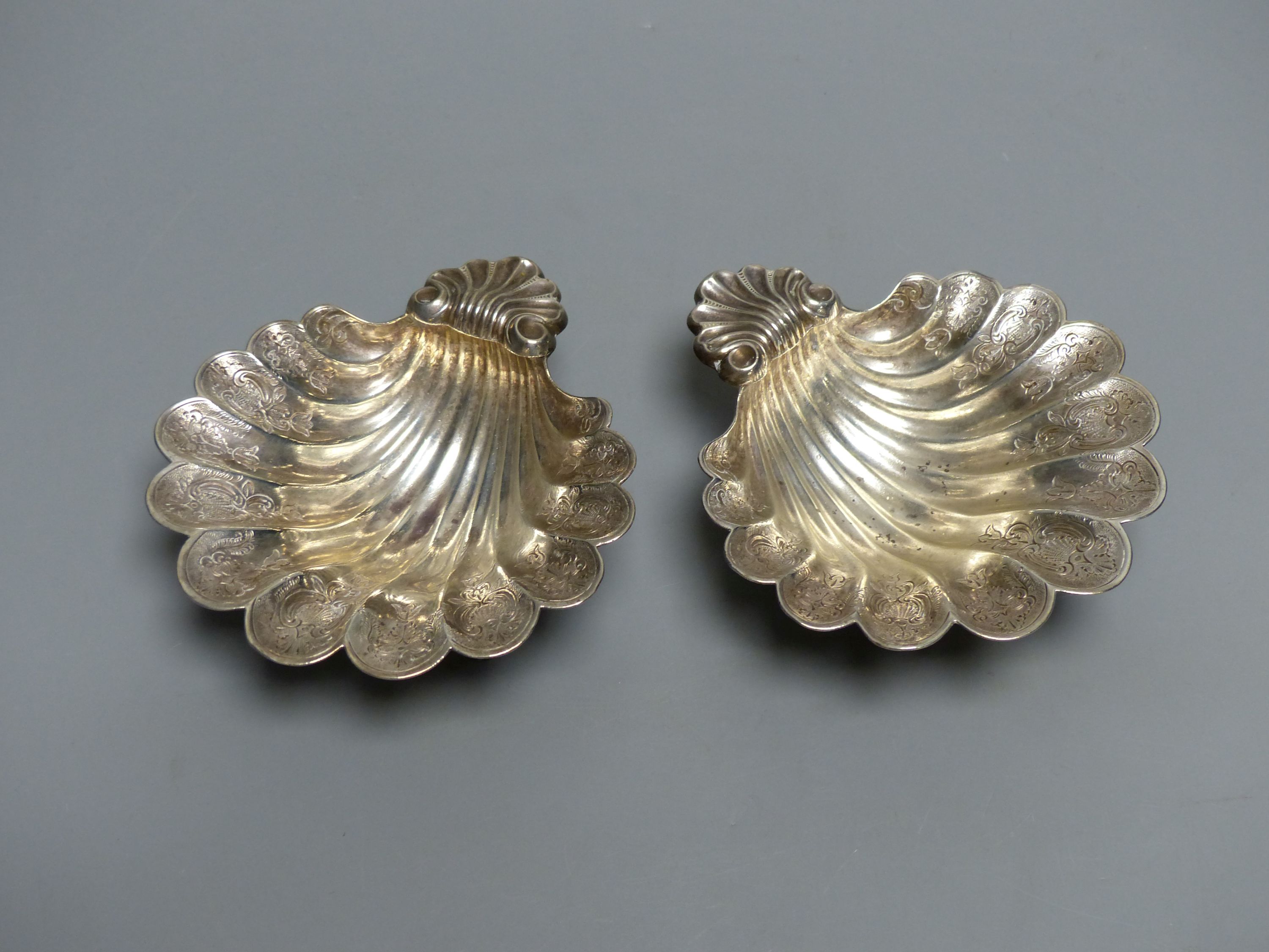 A pair of engraved scallop shell bon bon dishes on three scrolled feet, London 1934, 12.6cm, 9oz.